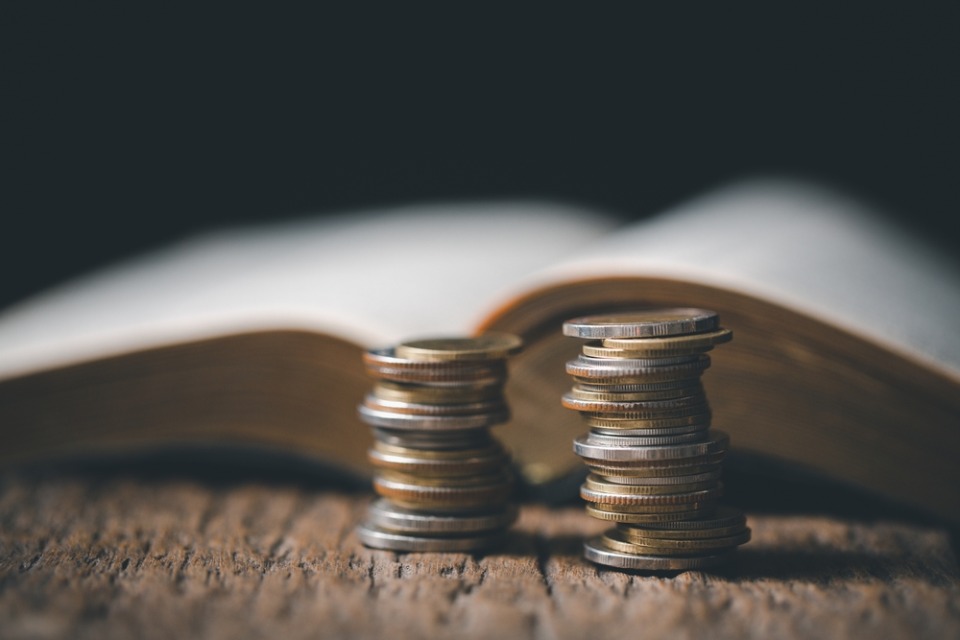 Monedas apiladas al lado de un libro abierto